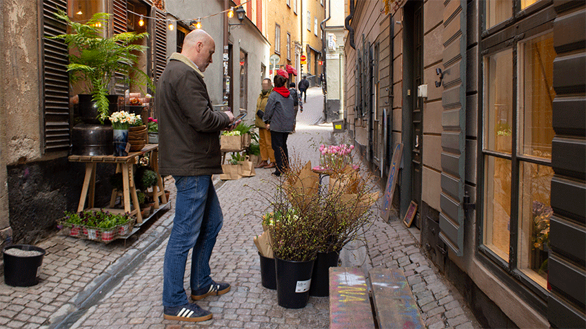 En man tittar i sin mobil när han står i en av Gamla stans gränder i Stockholm en tidig vårdag.