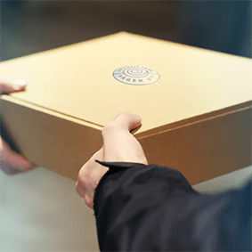 Ett brunt paket överlämnas mellan två händer