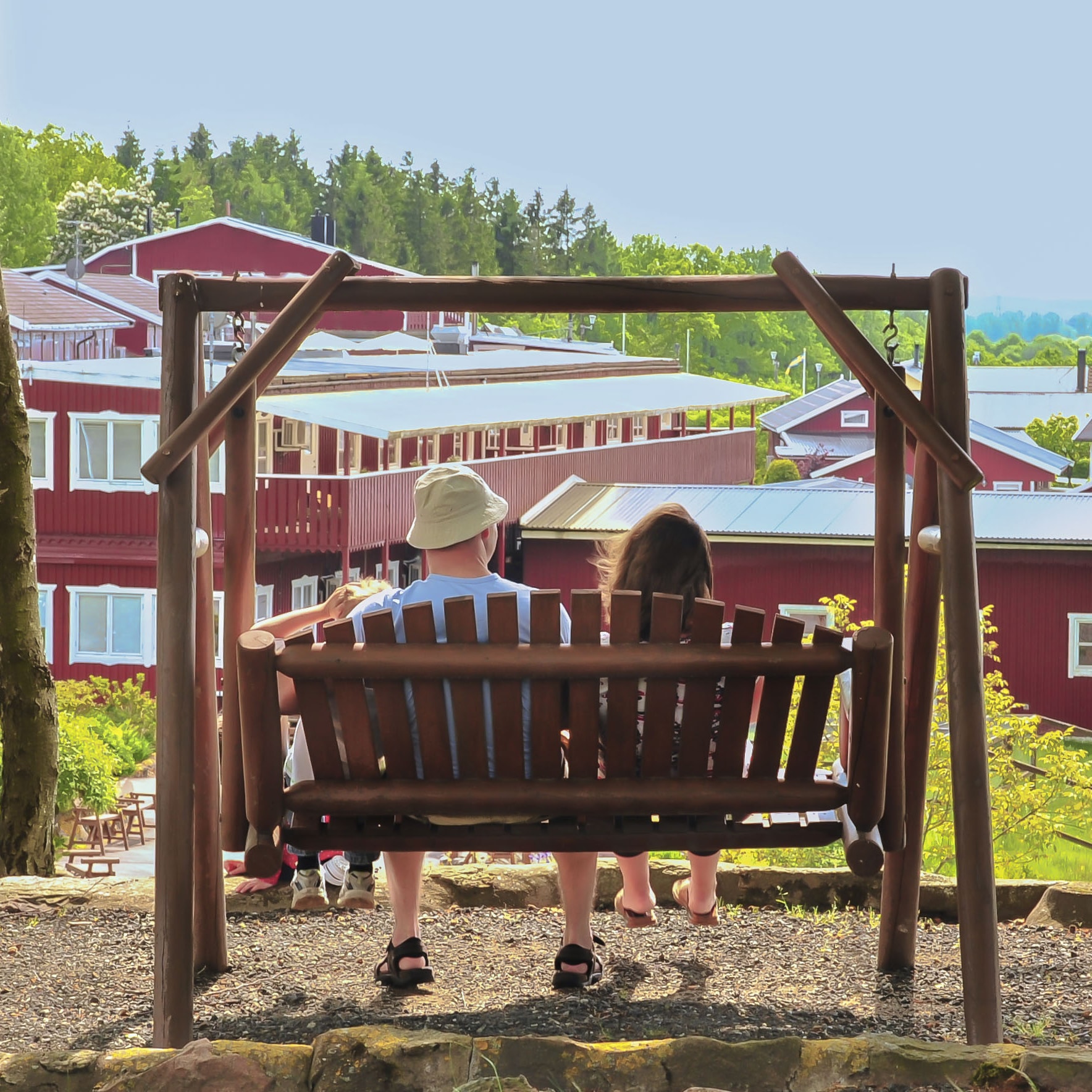Två barn sitter i en hammock och man ser dem bakifrån.