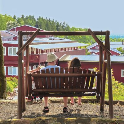 Två barn sitter i en hammock och man ser dem bakifrån.