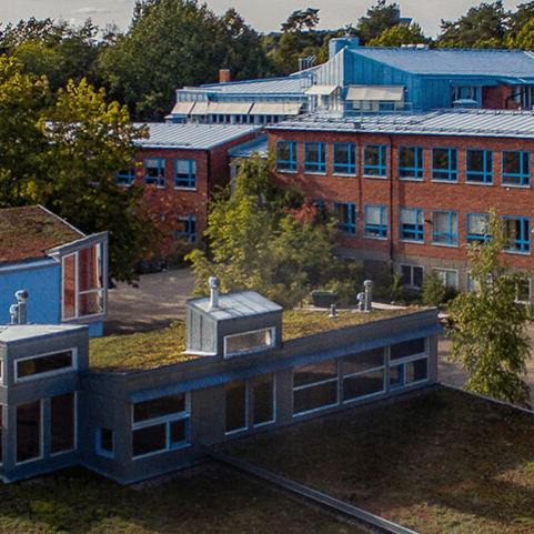 Bilden är tagen ovanifrån och visar några olika byggnader; röda högre och ett lägre hus.