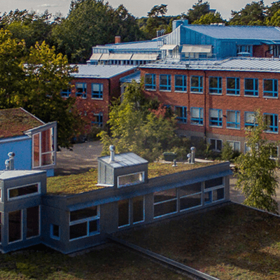 Bilden är tagen ovanifrån och visar några olika byggnader; röda högre och ett lägre hus.