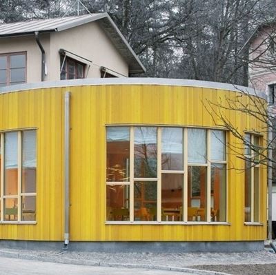 En gul rundad träbyggnad där träden saknar blad och det är mer grått ute.