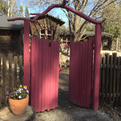 Två höga trädörrar dörrar som leder in till en gård.