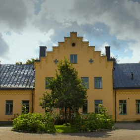 Ett gult hus som skyms av en liten ansad trädunge.