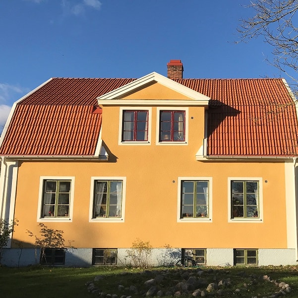 Ett gult hus med rött tak och en molnfri dag.